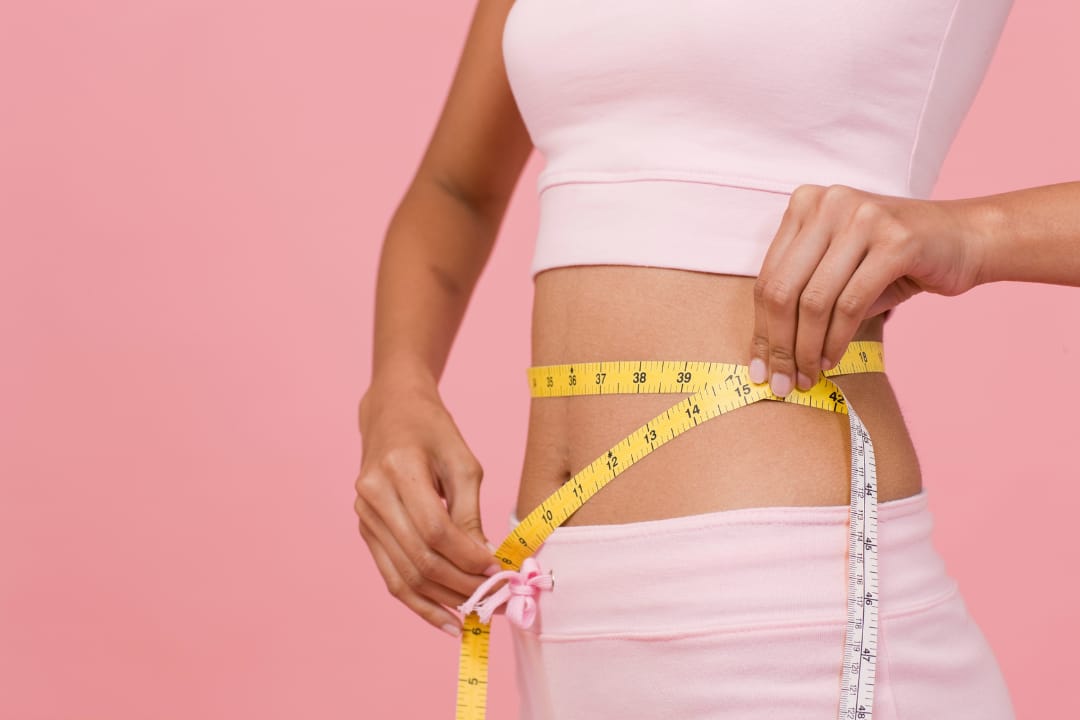 Mulher medindo a cintura com fita métrica